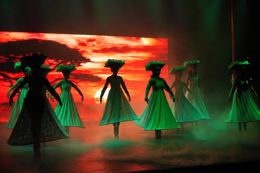Bailarinas com vestidos longos diante de pôr do sol na savana