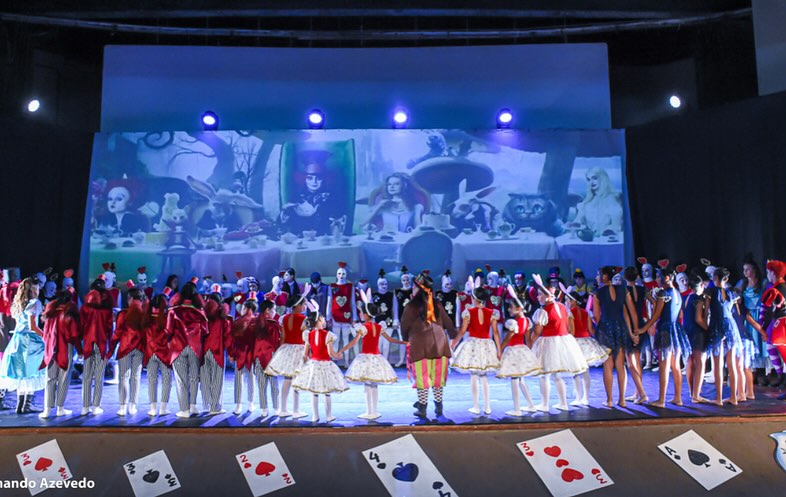 Cena ampla com elenco e cartas no chão no espetáculo Alice
