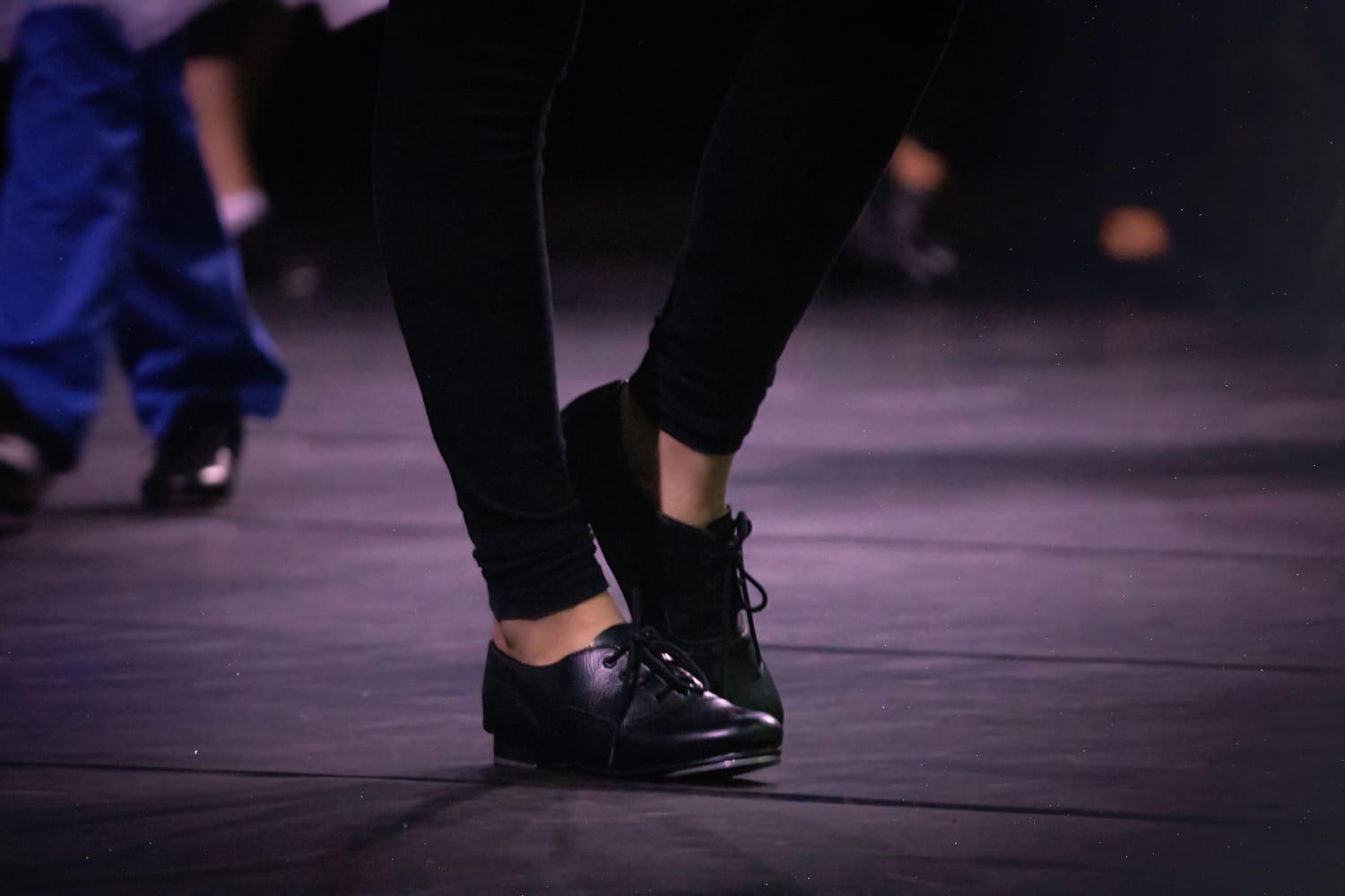 Close dos sapatos pretos de sapateado durante apresentação do Billy Elliot
