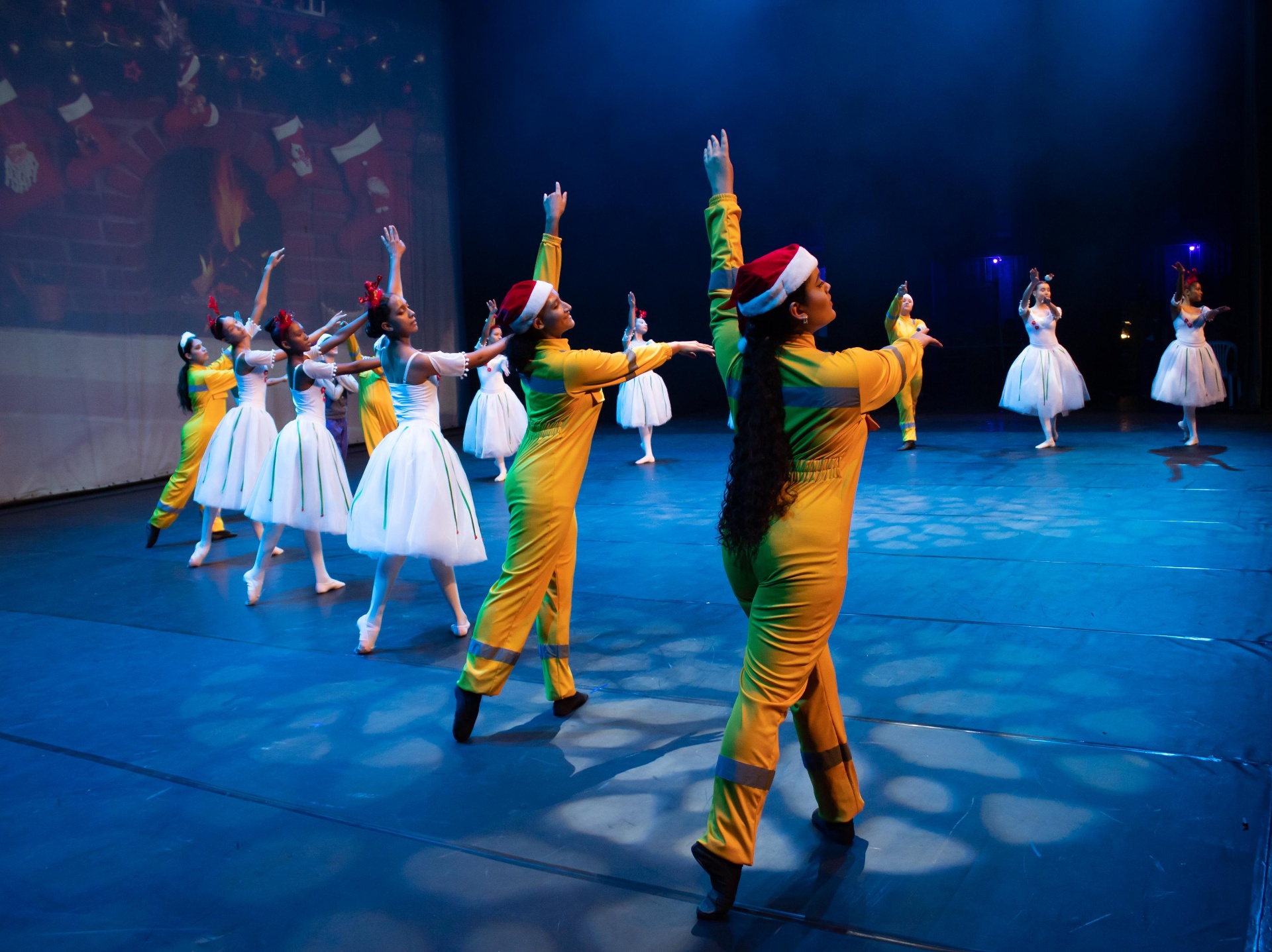 Cena natalina com mineiros e bailarinas dançando com gorros de Papai Noel no Billy Elliot