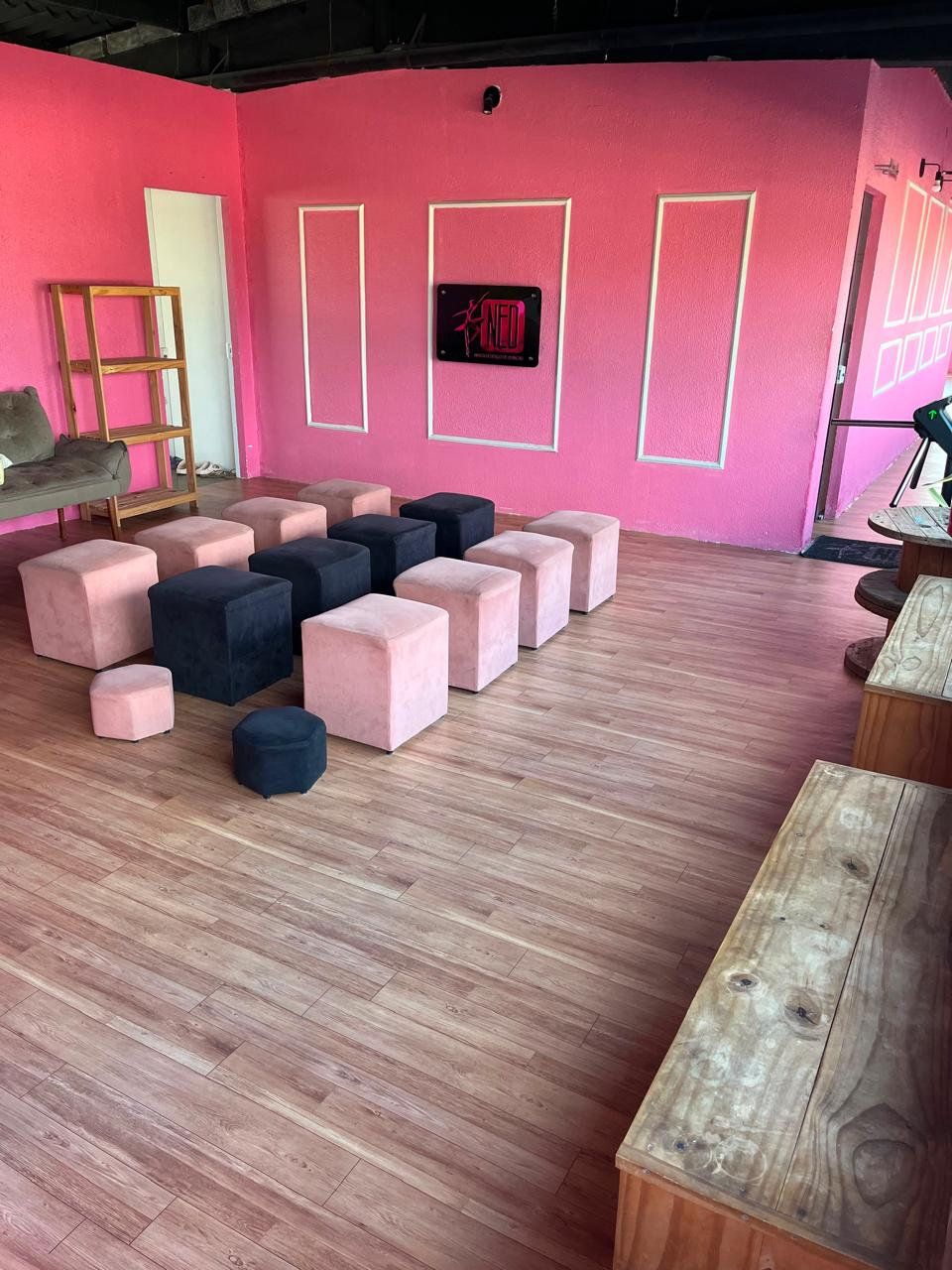 Sala de espera do NED com pufes rosa e pretos e quadro do logo NED