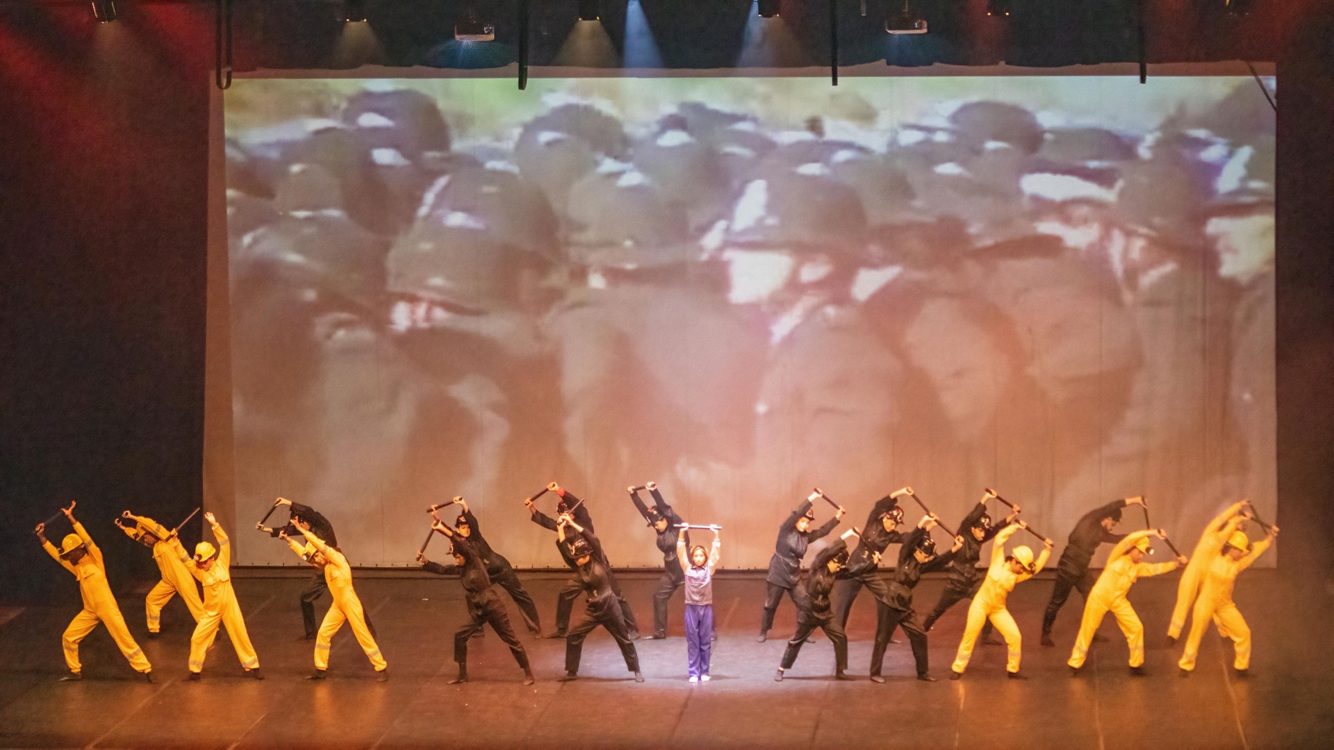 Cena da greve dos mineiros com marteladas e projeção ao fundo no Billy Elliot