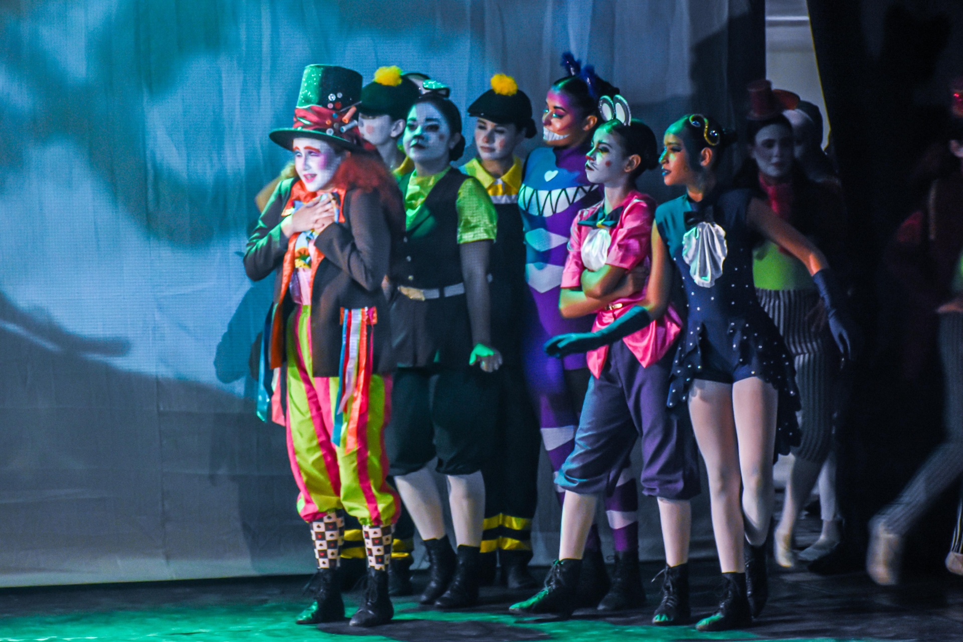 Elenco de personagens enfileirados em pose marcante no espetáculo Alice