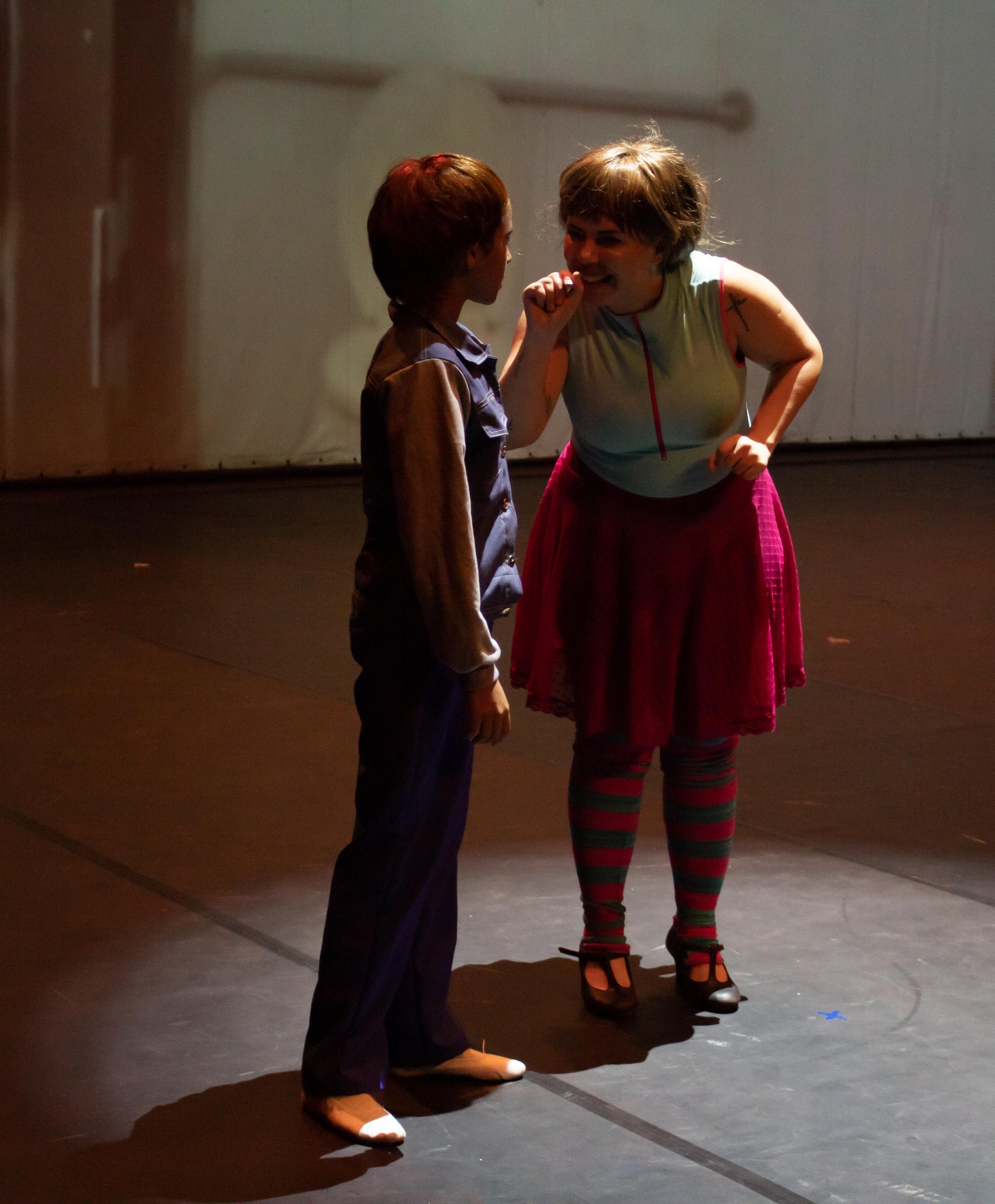 Billy conversando com amiga de meias listradas e saia rosa no Billy Elliot