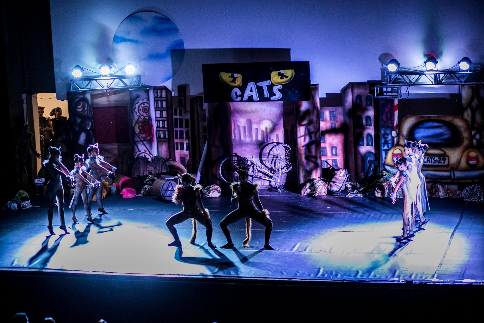 Visão ampla do palco do espetáculo Cats com a cenografia urbana e o letreiro CATS