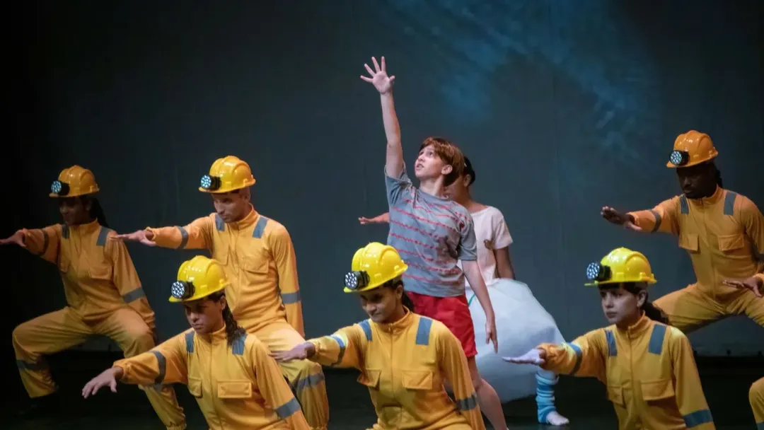 Billy entre mineiros em cena no espetáculo Billy Elliot