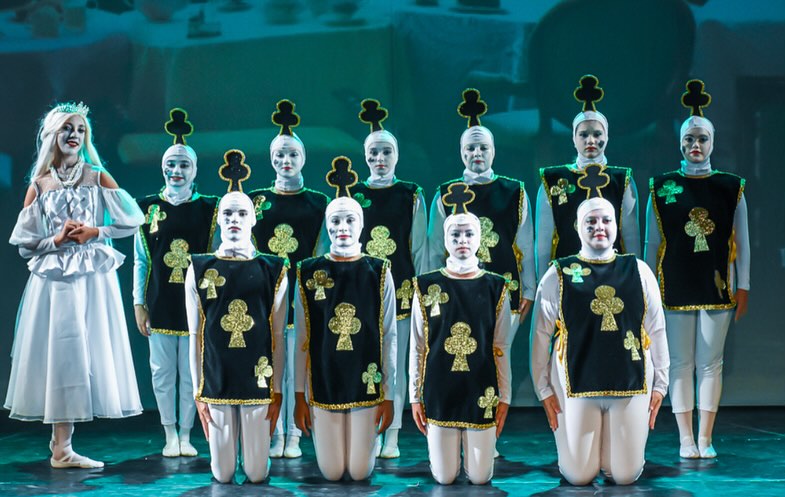 Bailarinos vestidos de cartas de paus em cena no Alice