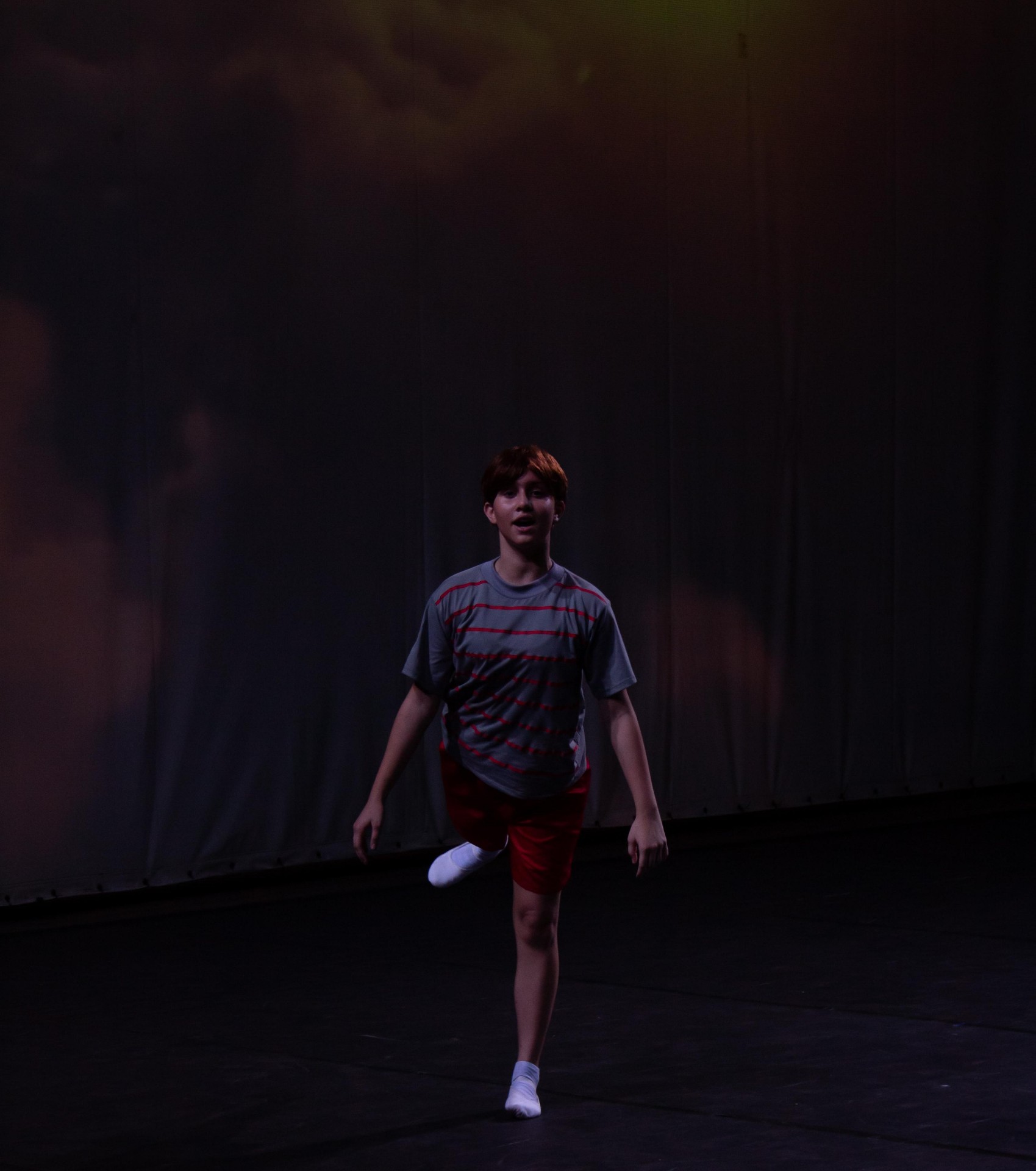 Billy em solo de dança com camiseta listrada no espetáculo Billy Elliot