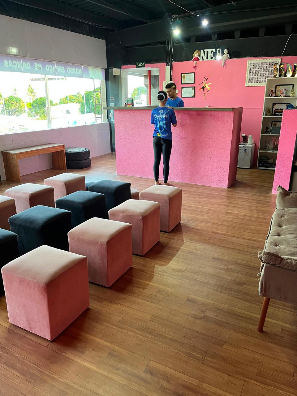 Recepção do NED com balcão rosa, poltronas e prateleira de troféus